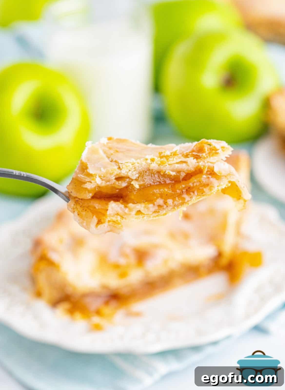 A fork holding up a perfect bite of Apple Slab Pie, showing the warm, spiced apple filling.