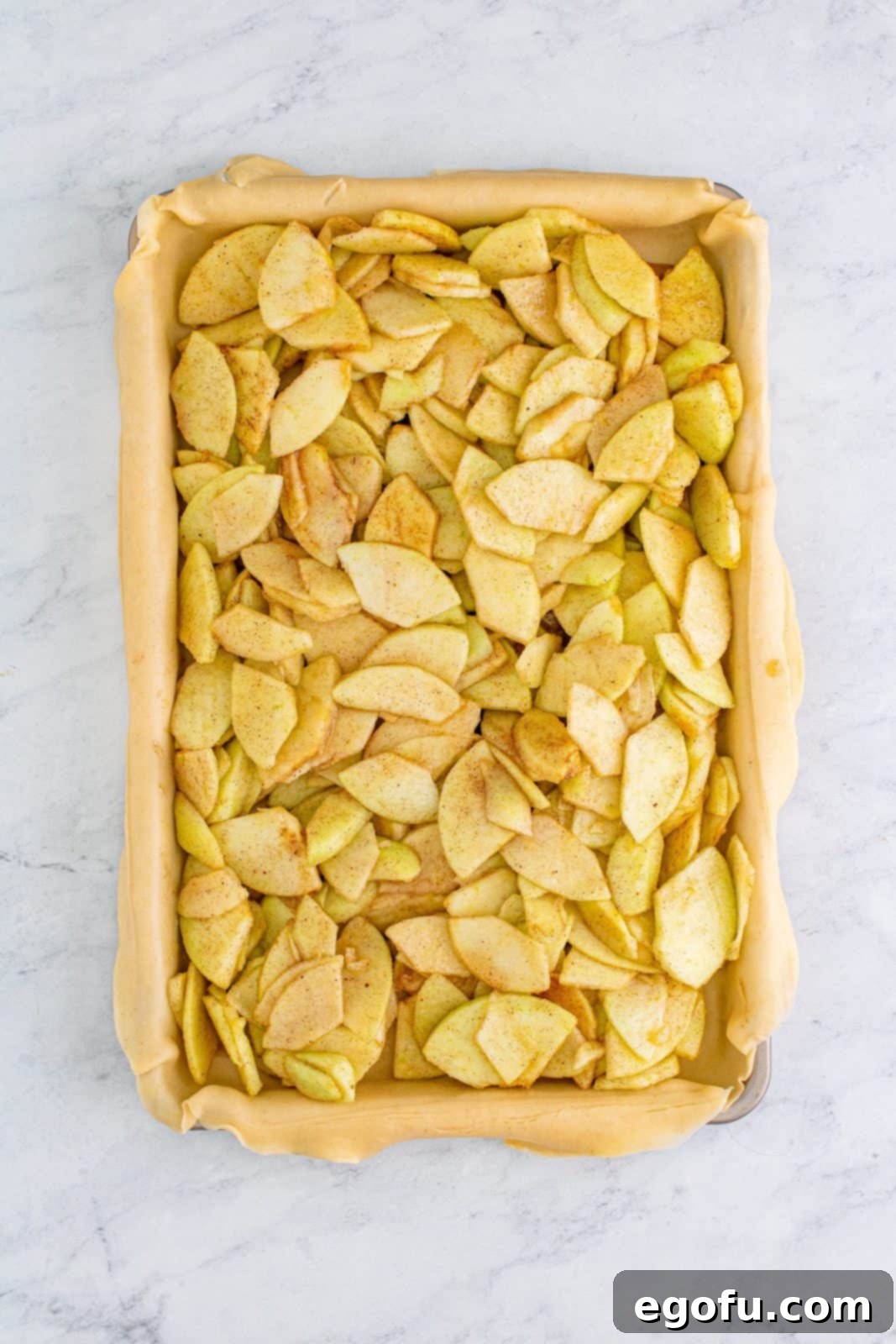 The spiced apple mixture spread smoothly and evenly over the bottom pie crust in the pan.