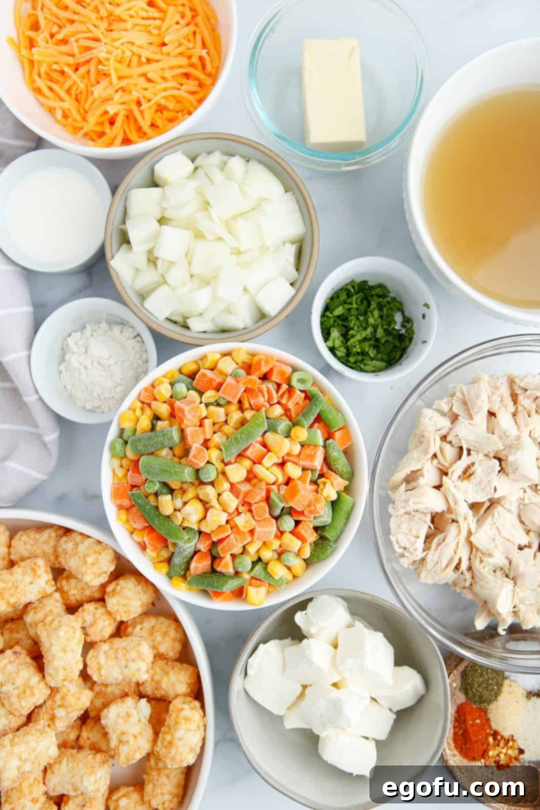 Ingredients needed: butter, rotisserie chicken, yellow onion, all-purpose flour, chicken stock, milk frozen mixed vegetables, cream cheese, paprika, onion powder, garlic powder, dried dill, dried thyme, salt, pepper, frozen tater tots, cheddar cheese and parsley.