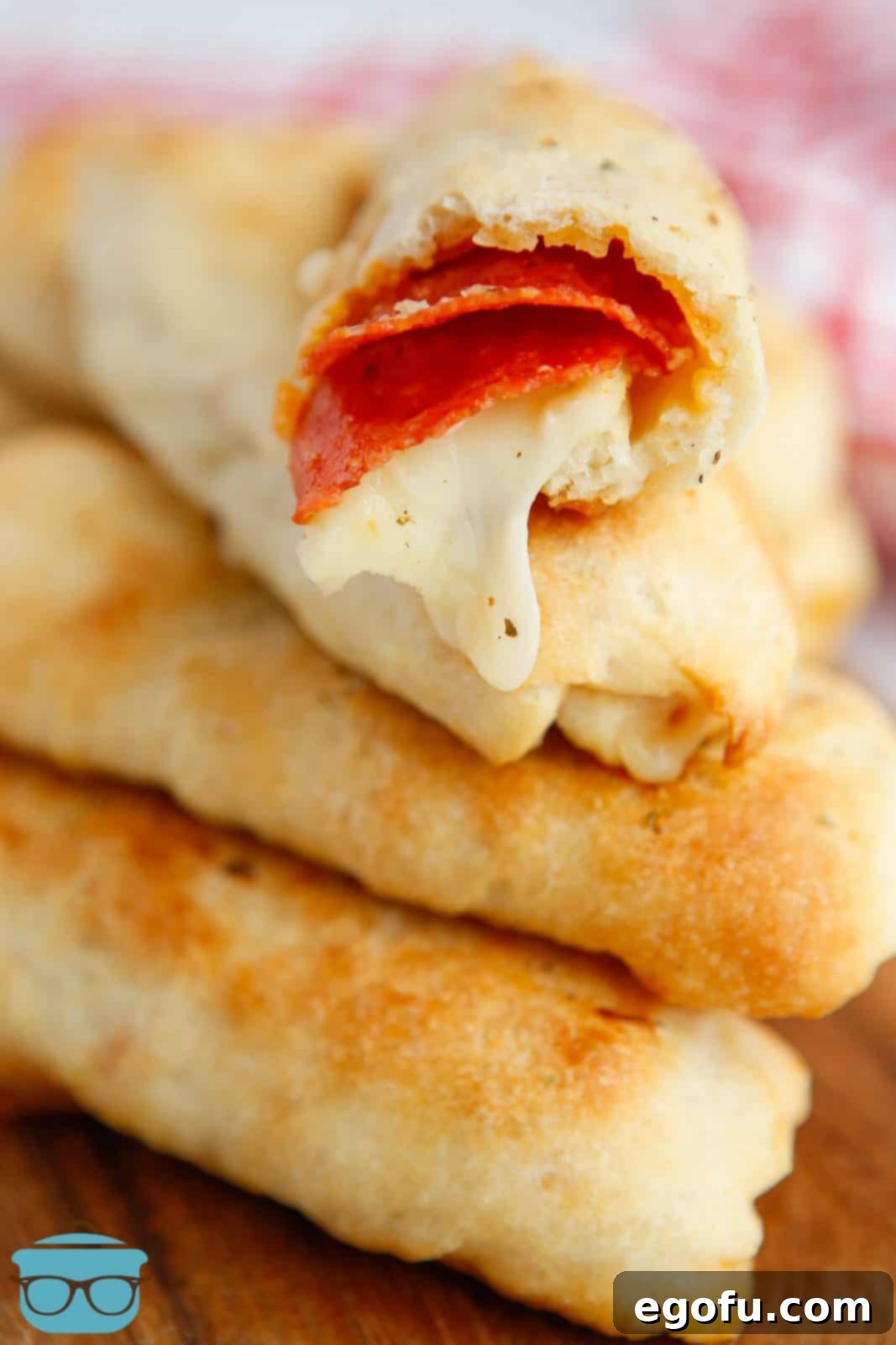 Stuffed Pizza Breadsticks 2 Stacked Pepperoni Pizza Breadsticks with bite taken out of top one showing inside.
