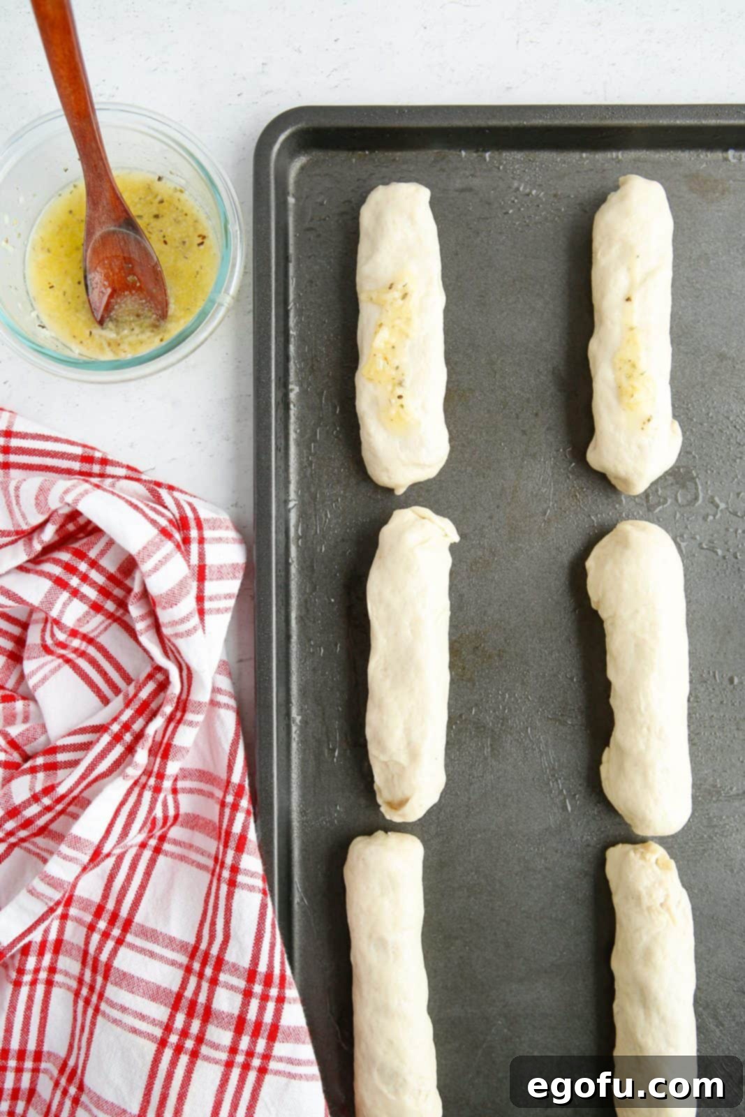 Stuffed Pizza Breadsticks 9 Wrapped up Pizza Roll Breadsticks on baking sheet brushed with garlic butter sauce.