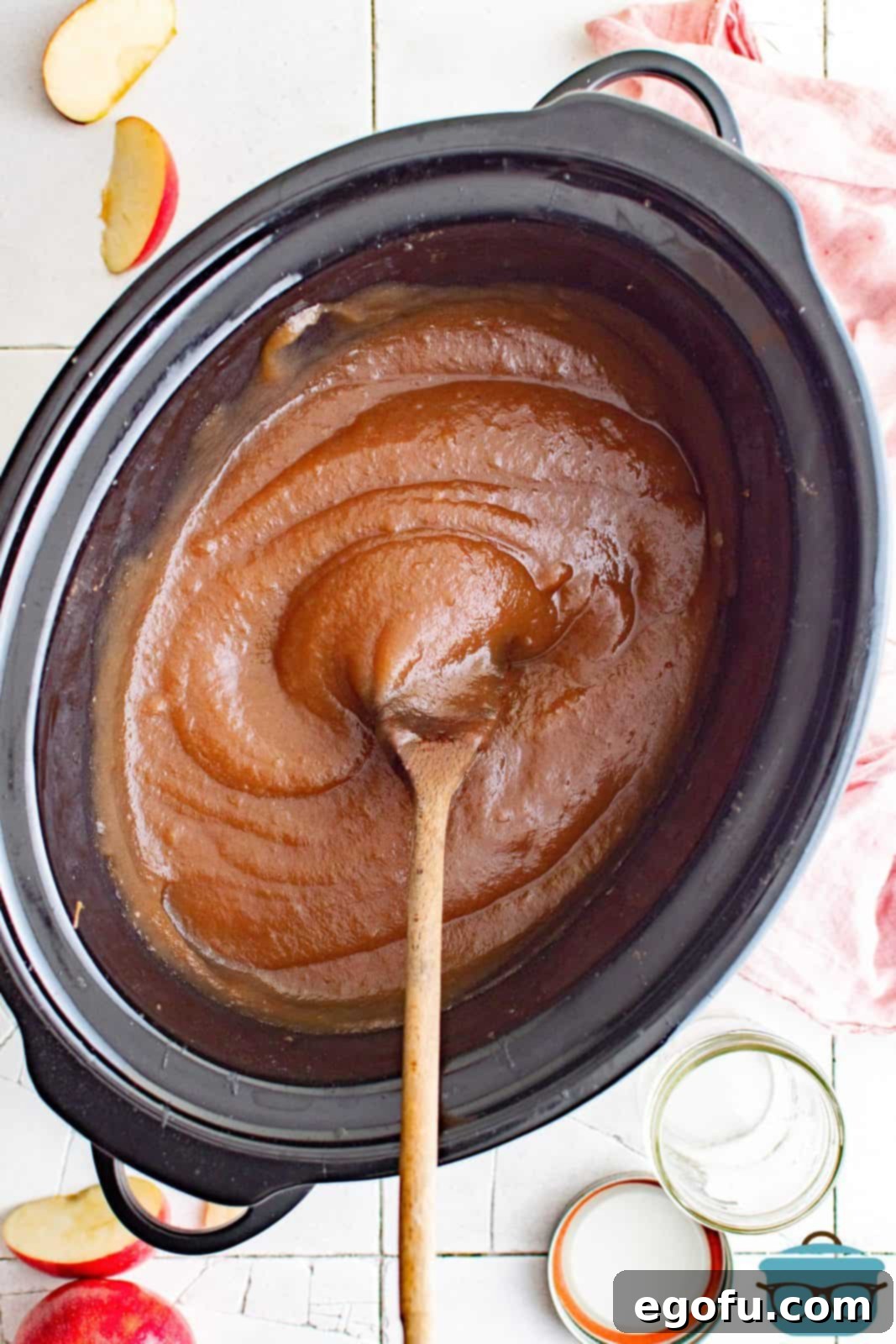 Overhead of smooth Slow Cooker Apple Butter in slow cooker with wooden spoon.