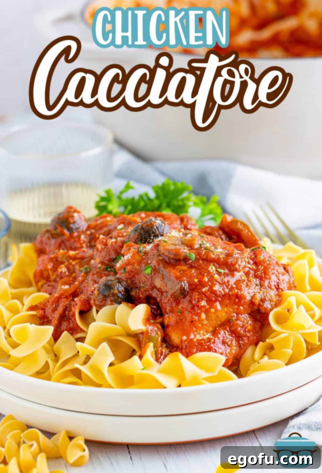 Chicken Cacciatore over noodles on a white plate, ready to be served.