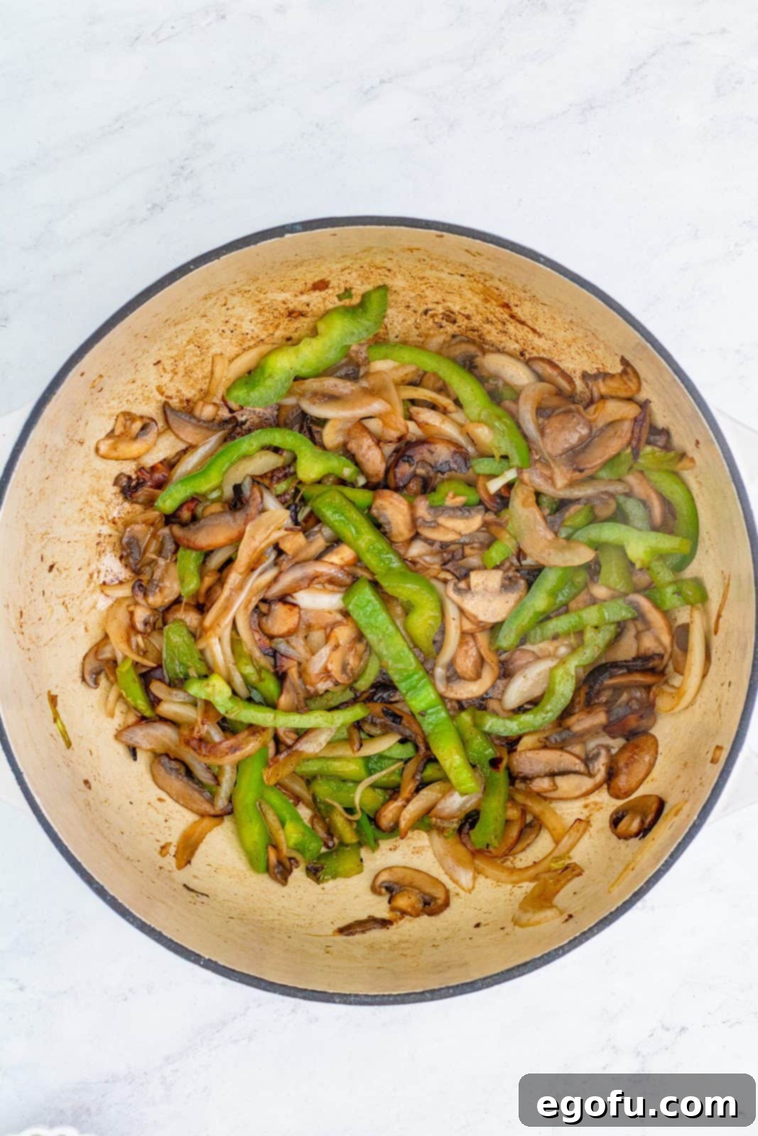 Onion, bell pepper, and mushrooms cooking in a Dutch oven until softened.