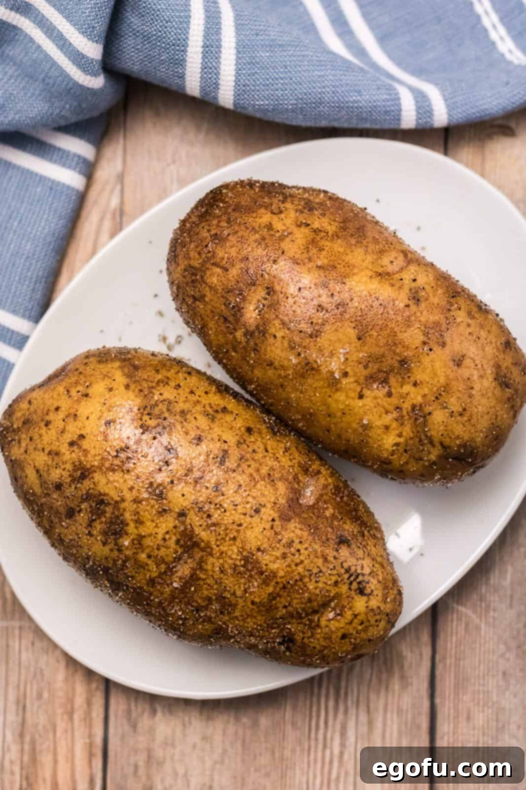 Two potatoes rubbed with oil, salt and pepper.