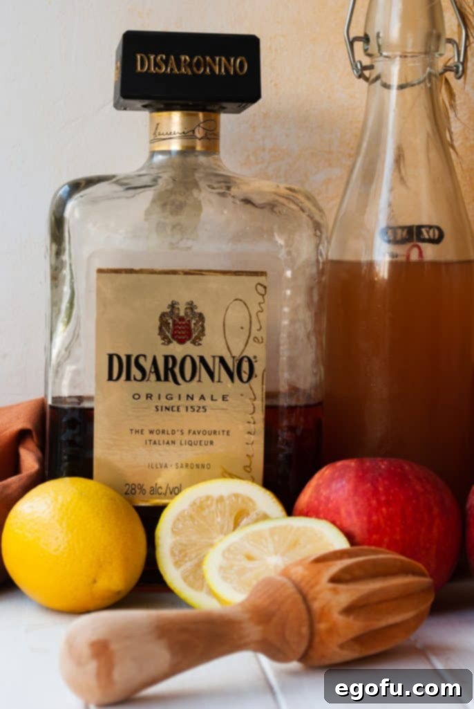 Ingredients needed: amaretto liqueur, fresh lemon juice, apple cider, and ice, laid out clearly for preparation.