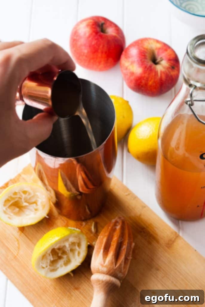 Apple cider being poured into the cocktail shaker, completing the liquid ingredients.