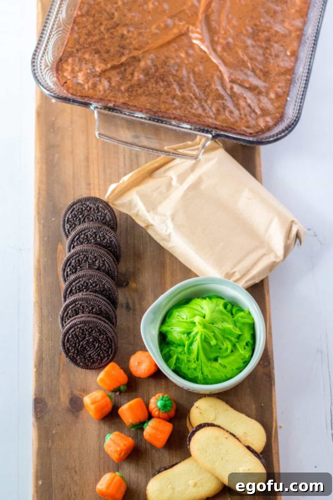 Ingredients needed: brownies, chocolate pudding mix, milk, oreos, milano cookies, chocolate frosting, green frosting and pumpkin candies, laid out on a table.