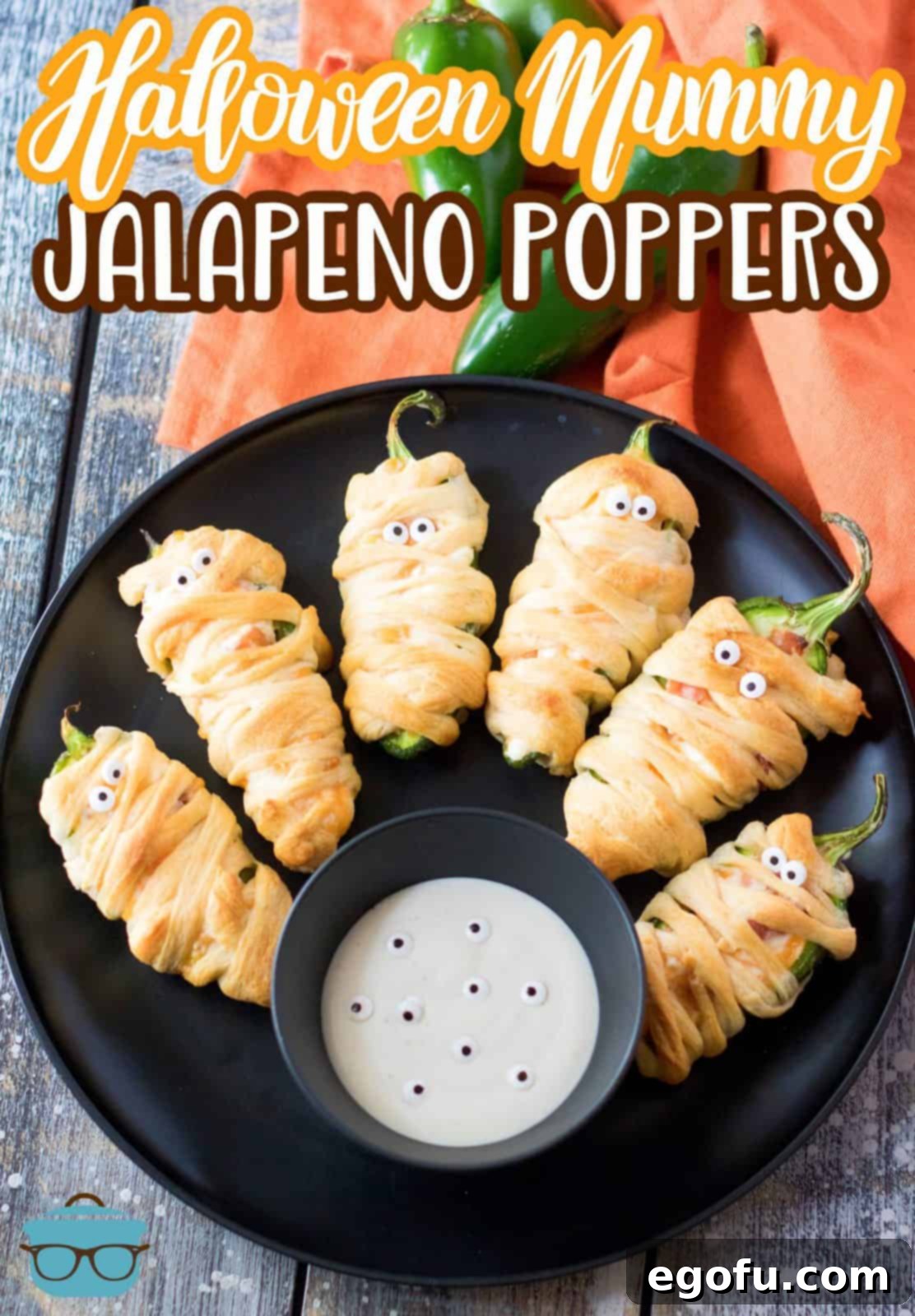 Mummy-Wrapped Jalapeño Poppers 8 Pinterest image of finished Halloween Mummy Jalapeno Poppers on black plate with dipping sauce.