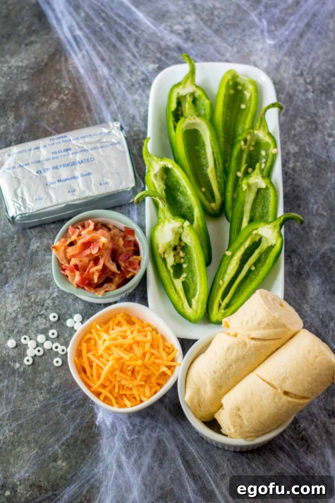 Mummy-Wrapped Jalapeño Poppers 3 Ingredients needed: cream cheese, cheddar cheese, bacon, jalapeños, crescent rolls and candy eyes.