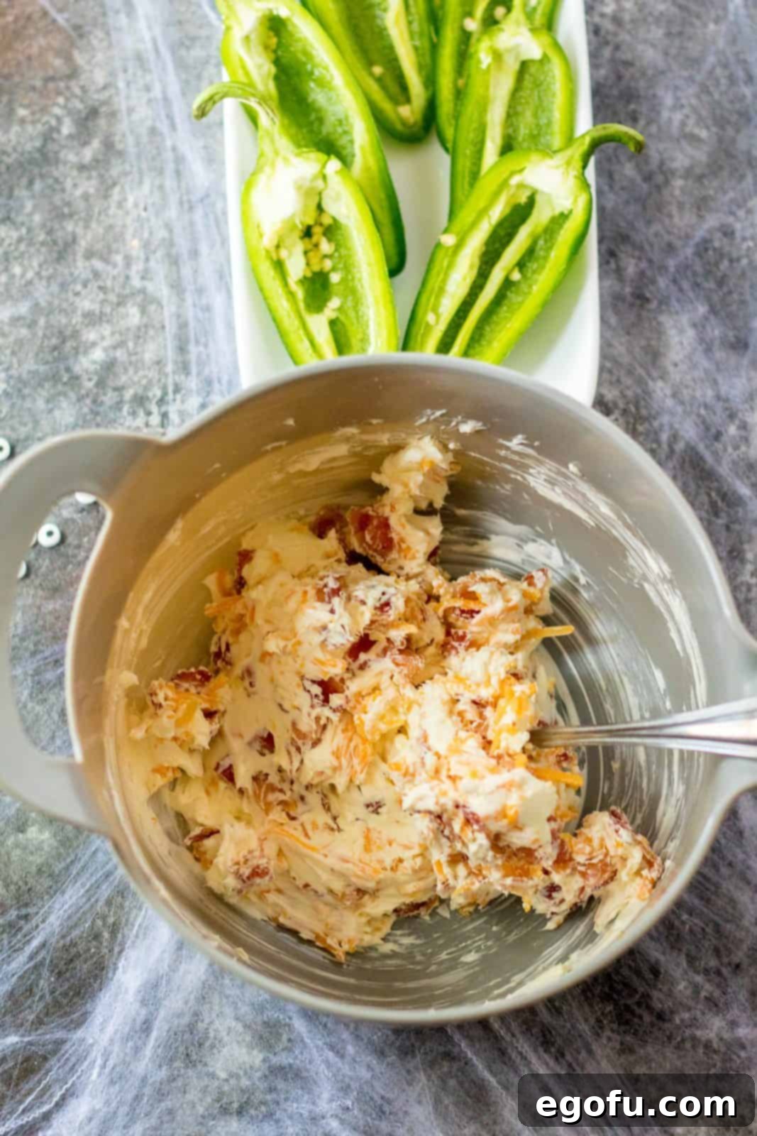 Mummy-Wrapped Jalapeño Poppers 4 Cream cheese, cheddar cheese and bacon mixed together in bowl.