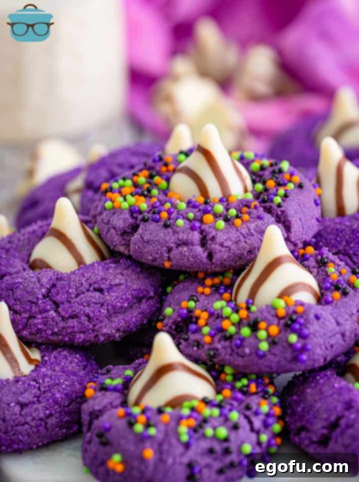 Close up stacked Halloween Witch Hat Cookies stacked on platter, showcasing their vibrant purple color and chocolate tops.