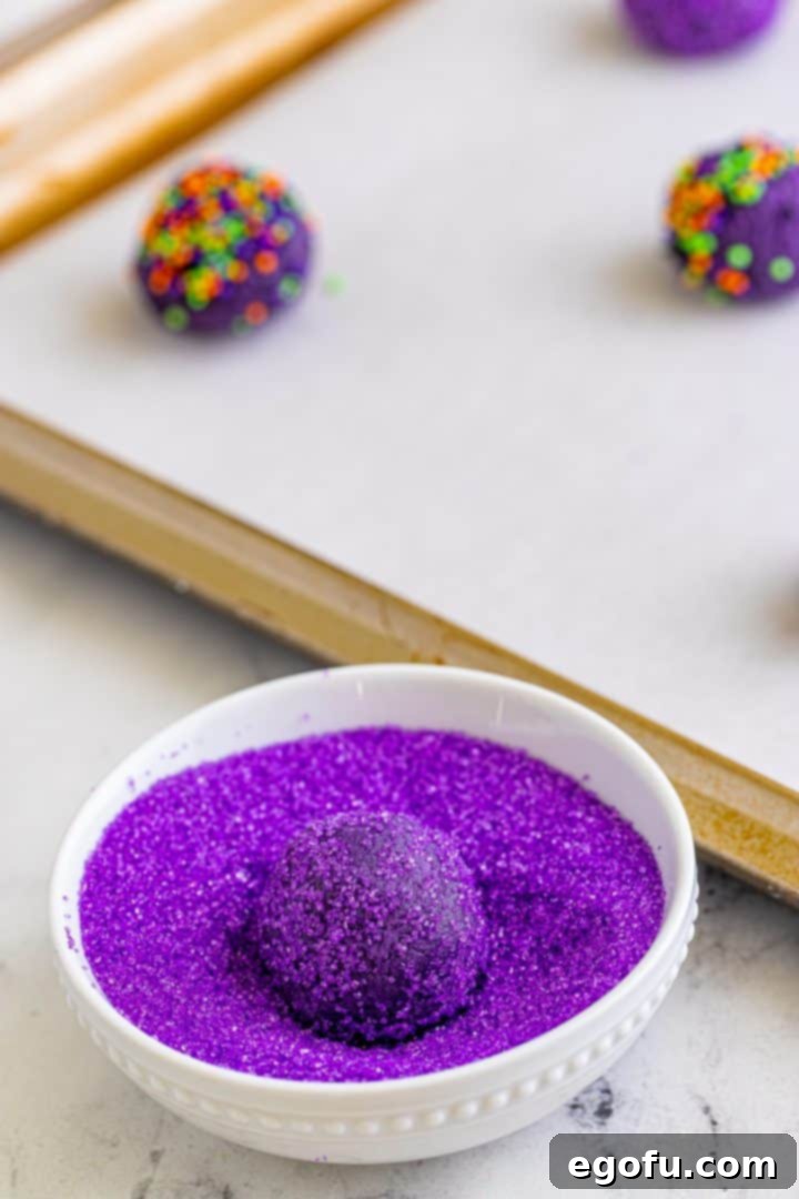 Cookie dough balls being rolled into sugar and sprinkles, demonstrating the coating process.