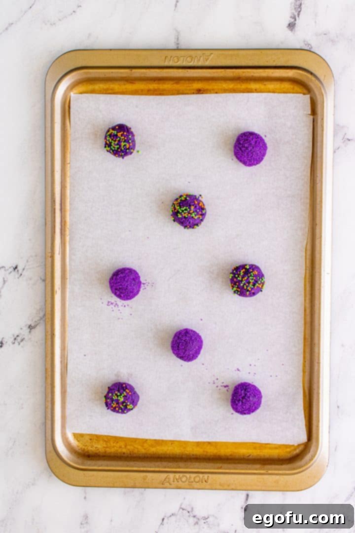 Cookie dough balls placed on lined baking sheet, perfectly spaced and ready for baking in the oven.