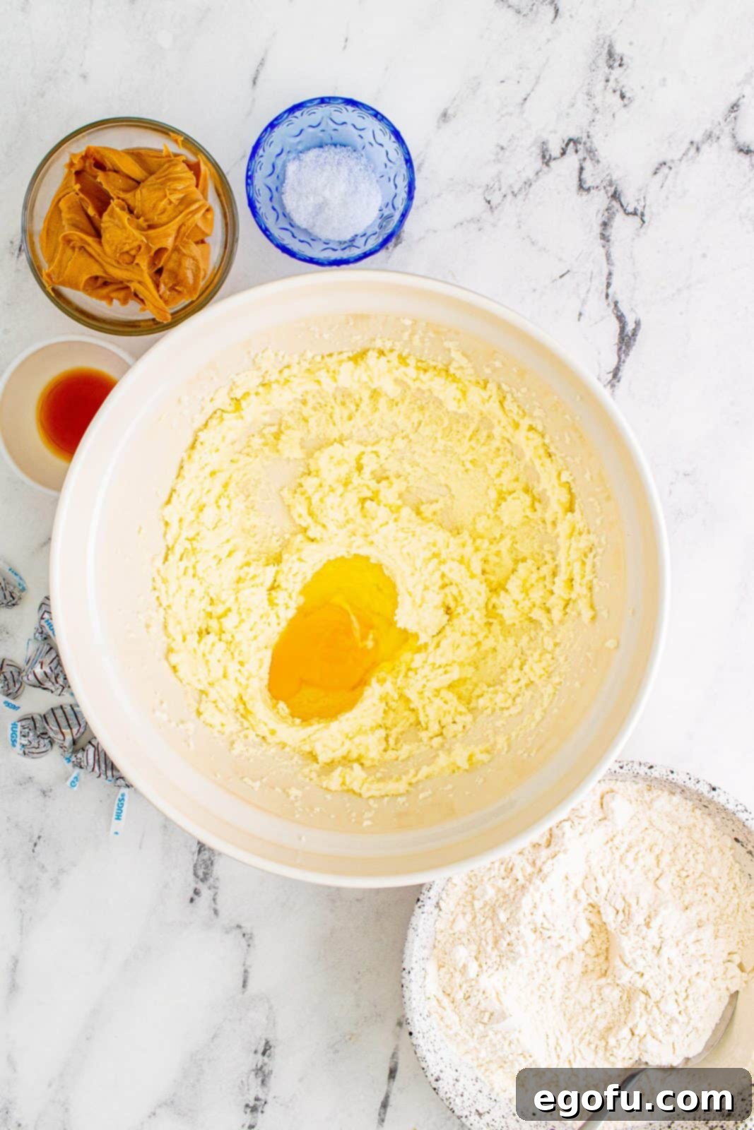 Egg added to beaten butter and sugar mixture, showing a creamy, yellow consistency.