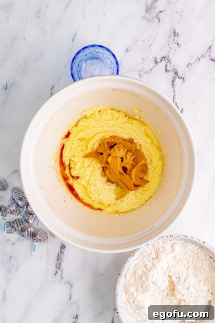 Peanut butter and vanilla added to butter mixture, being combined thoroughly.