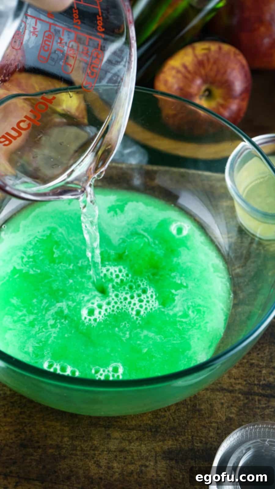 Vodka and lime juice being added to jell-o mixture in bowl.