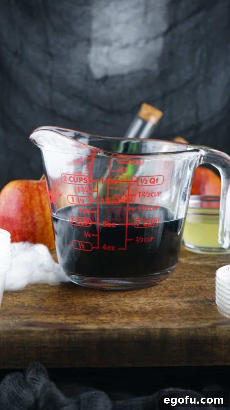 Remaining jell-o mixture with black food coloring added in measuring cup.