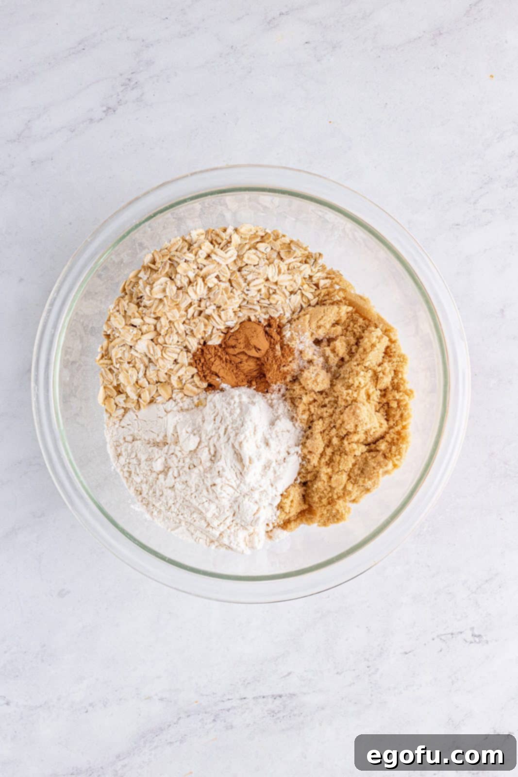 Brown sugar, flour, oats, pumpkin spice, and salt are combined in a clear bowl for the streusel topping.