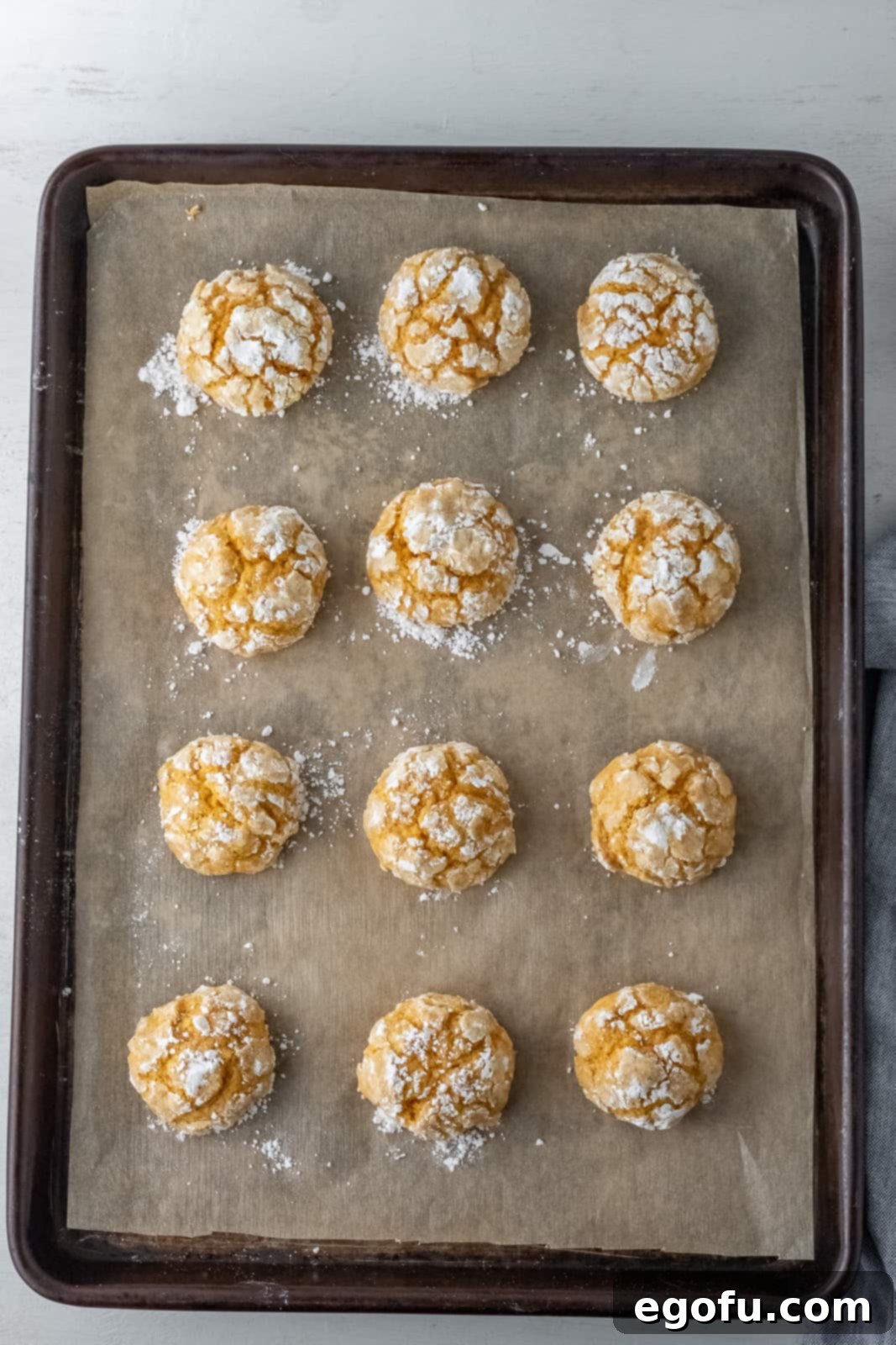 Fall Pumpkin Crinkle Delights 11 A batch of perfectly baked Pumpkin Crinkle Cookies, displaying their beautiful cracked tops, cooling on a natural parchment paper-lined baking sheet.