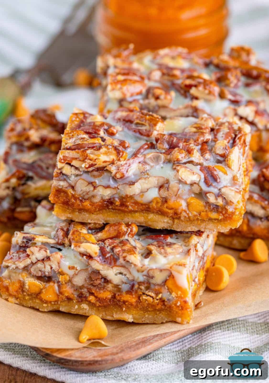 Autumn Magic Pumpkin Bars 2 Stacked Pumpkin Magic Bars on parchment paper, showcasing their delicious layers and golden-brown tops.