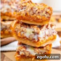 Autumn Magic Pumpkin Bars 14 Stacked square image of Pumpkin Magic Bars on parchment paper, emphasizing their layers.