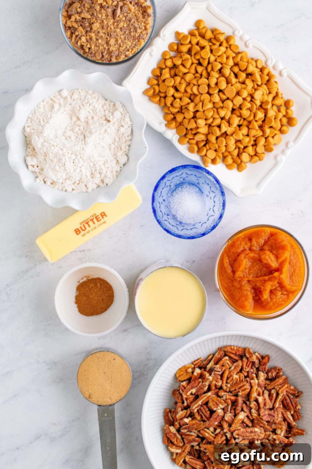 Autumn Magic Pumpkin Bars 4 Ingredients needed for Pumpkin Magic Bars: unsalted butter, light brown sugar, all-purpose flour, pumpkin pie spice, fine sea salt, canned pumpkin pie filling, butterscotch chips, toffee bits, chopped pecans, and sweetened condensed milk, neatly arranged for preparation.