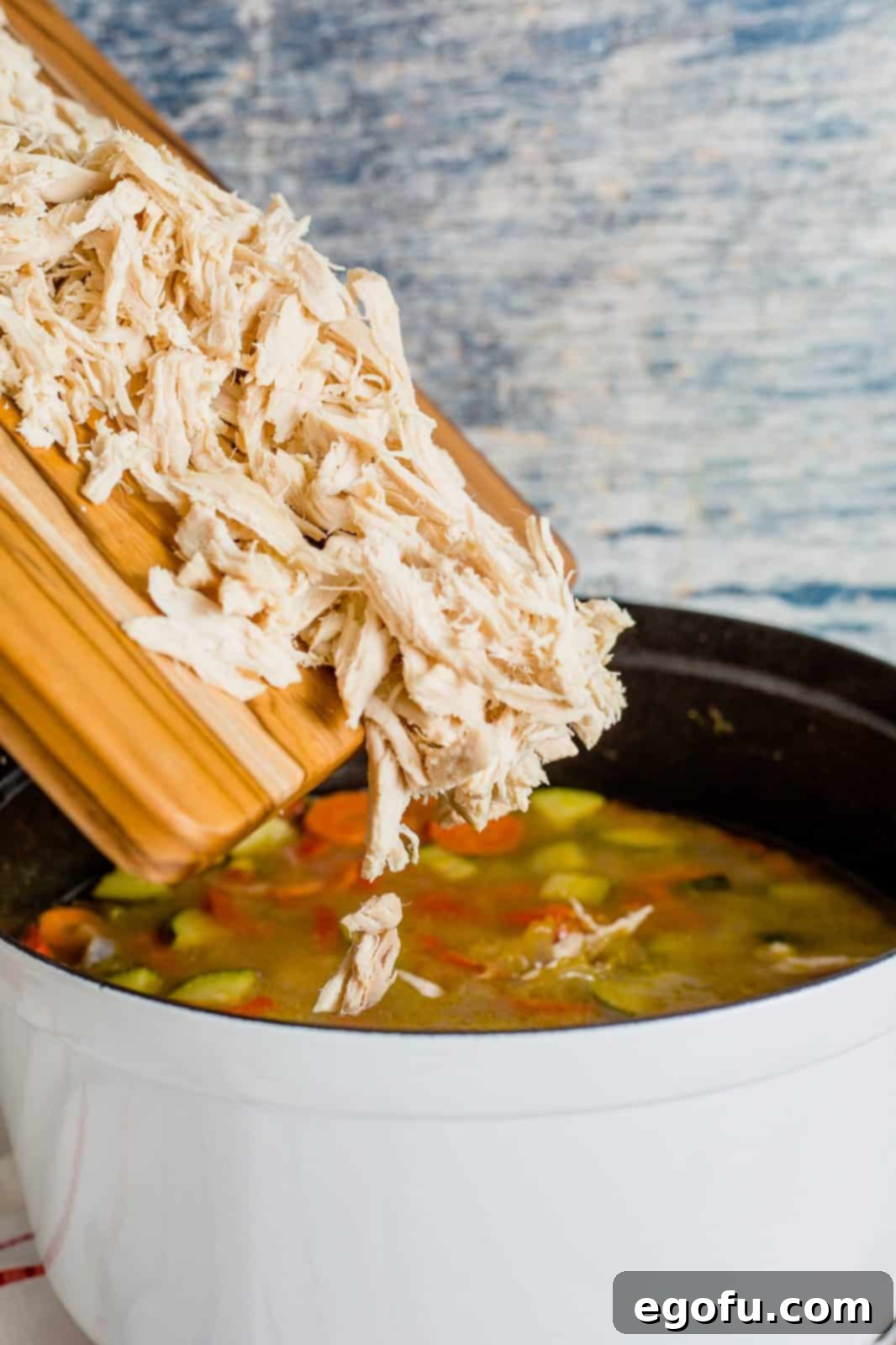 Golden Harvest Chicken and Rice Soup 9 Shredded chicken being returned to the pot of Harvest Chicken and Rice Soup, ready to be stirred in.