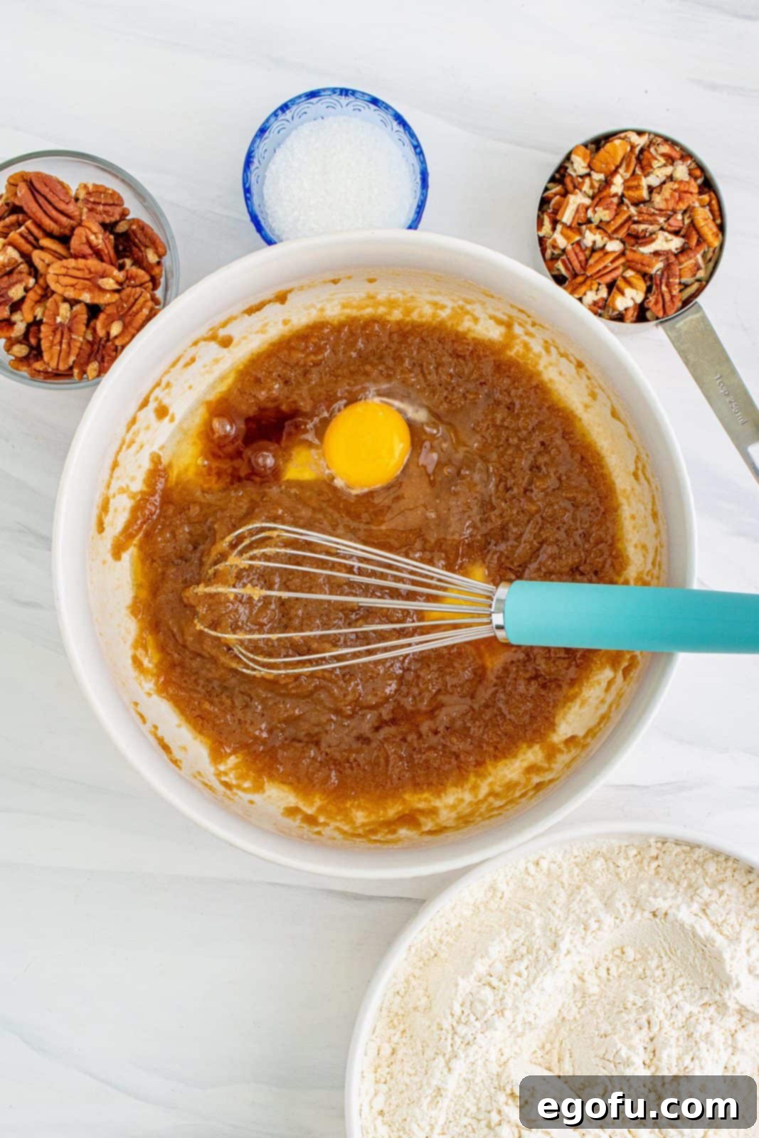 Egg and vanilla and butter extracts added to whisked together butter and sugar mixture in bowl.