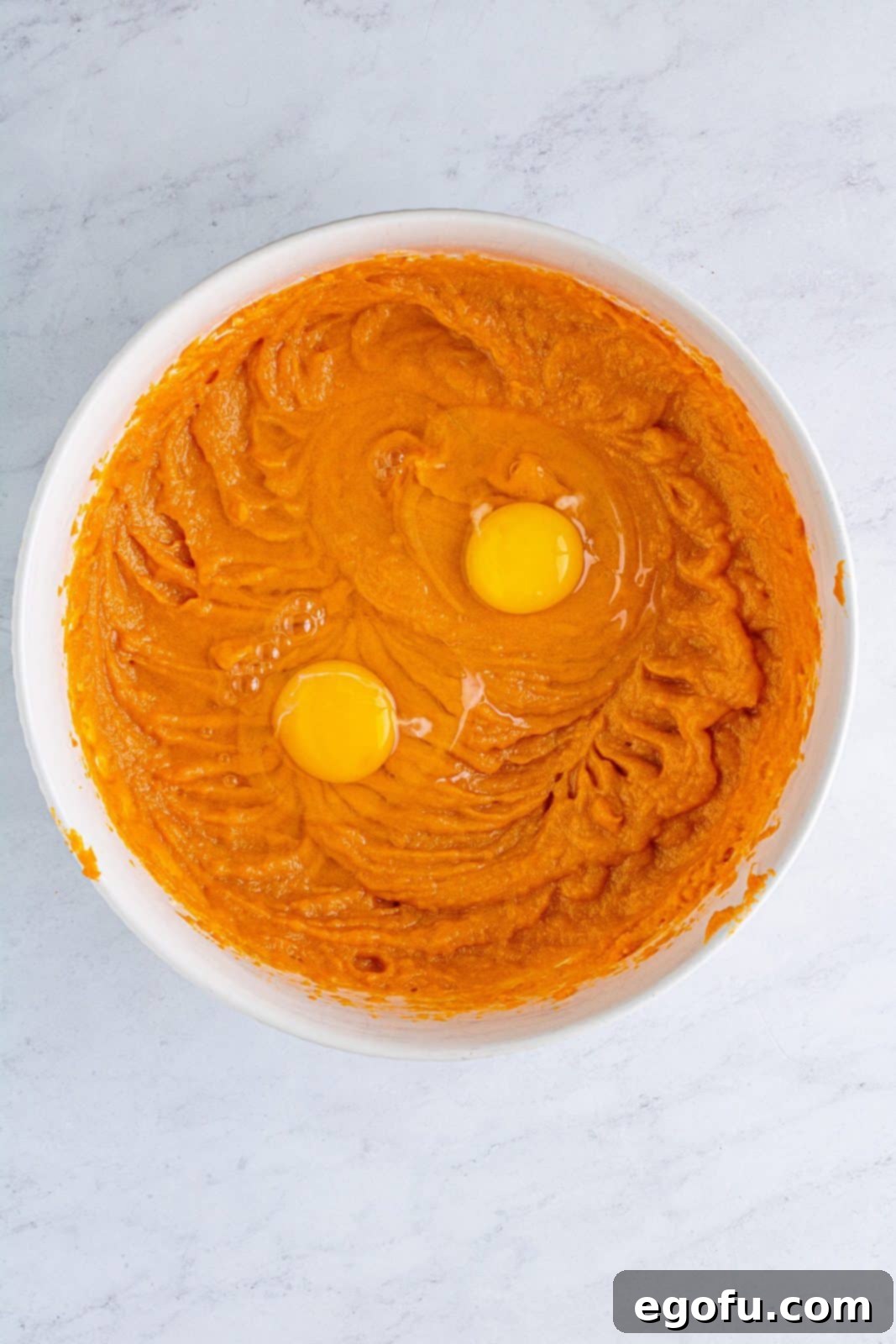 Velvet Sweet Potato Dream Pie 8 Eggs added to sweet potato mixture in bowl.