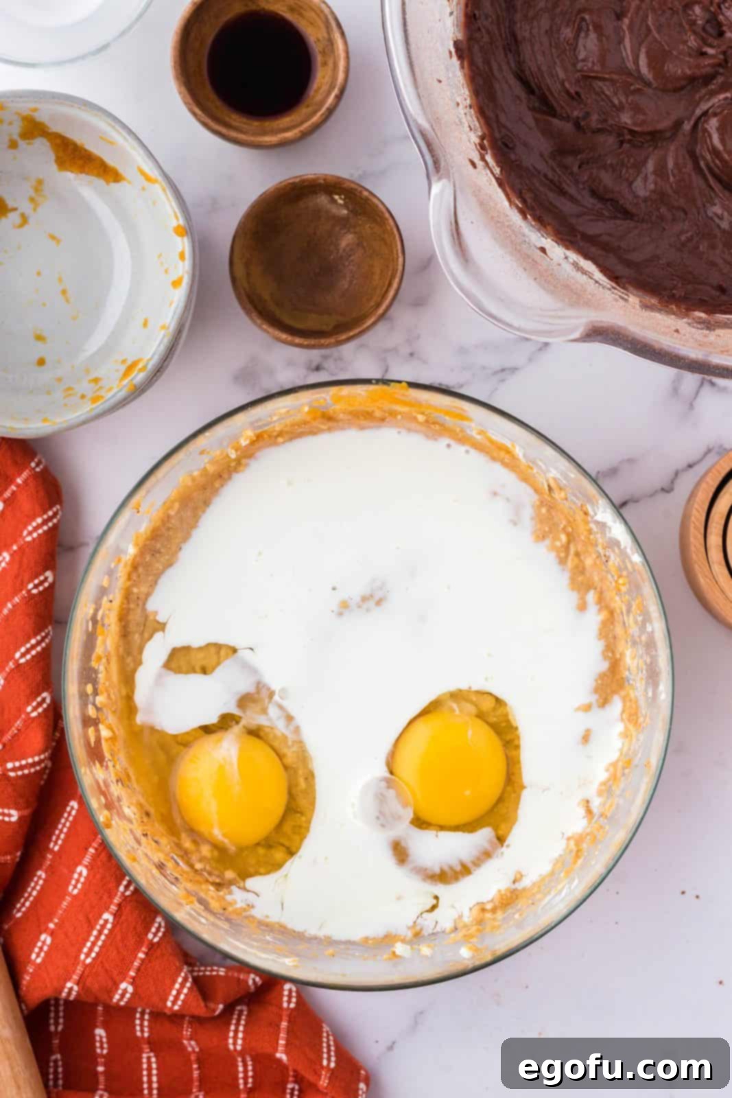 Eggs, vanilla extract, and heavy whipping cream added to the blended cream cheese and pumpkin mixture, forming the complete pumpkin swirl layer.