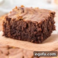 Square image of a single Pumpkin Swirl Brownie on a wooden server, ready to be enjoyed.