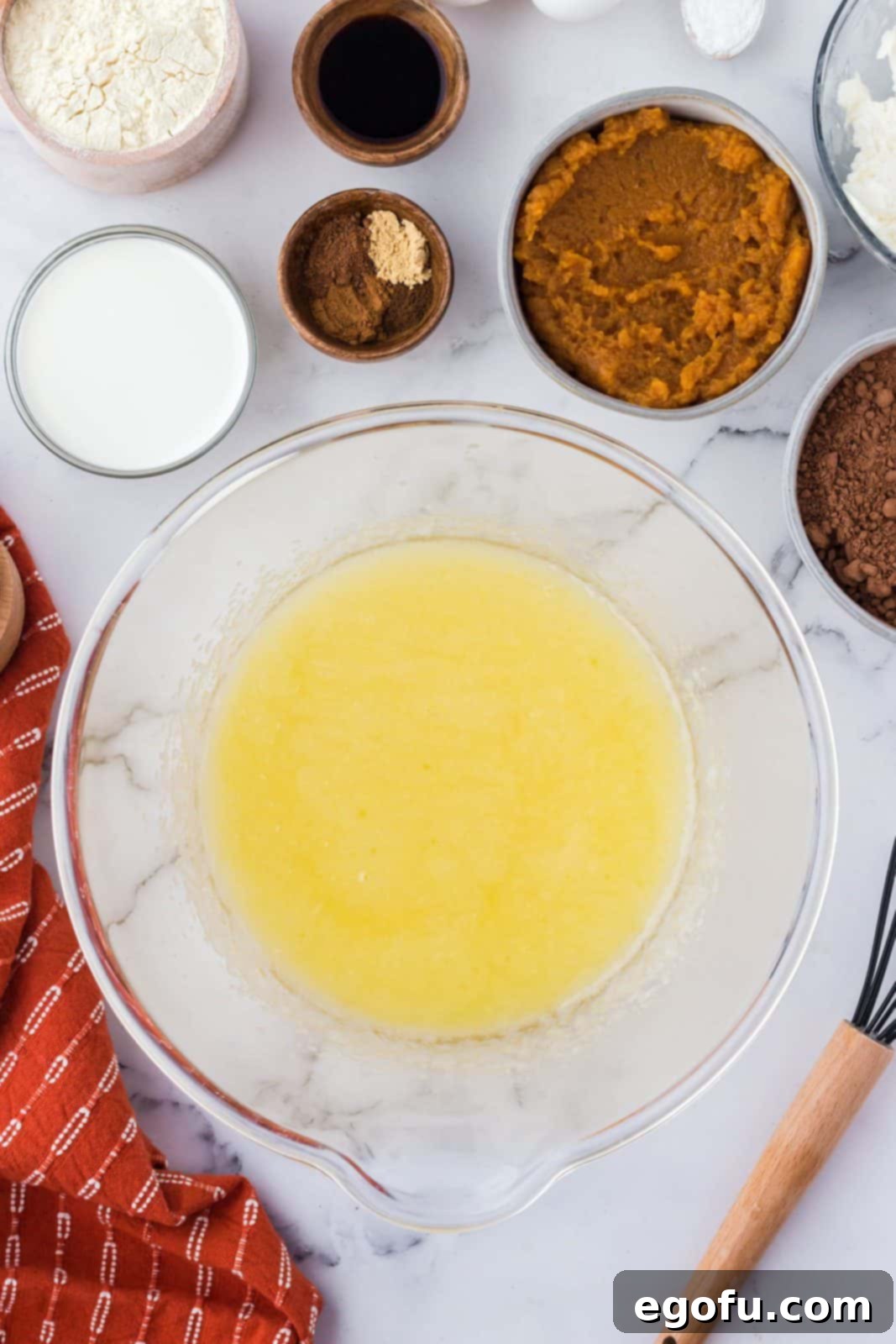 Melted butter and granulated sugar thoroughly combined in a clear mixing bowl, forming a smooth base for the brownie batter.