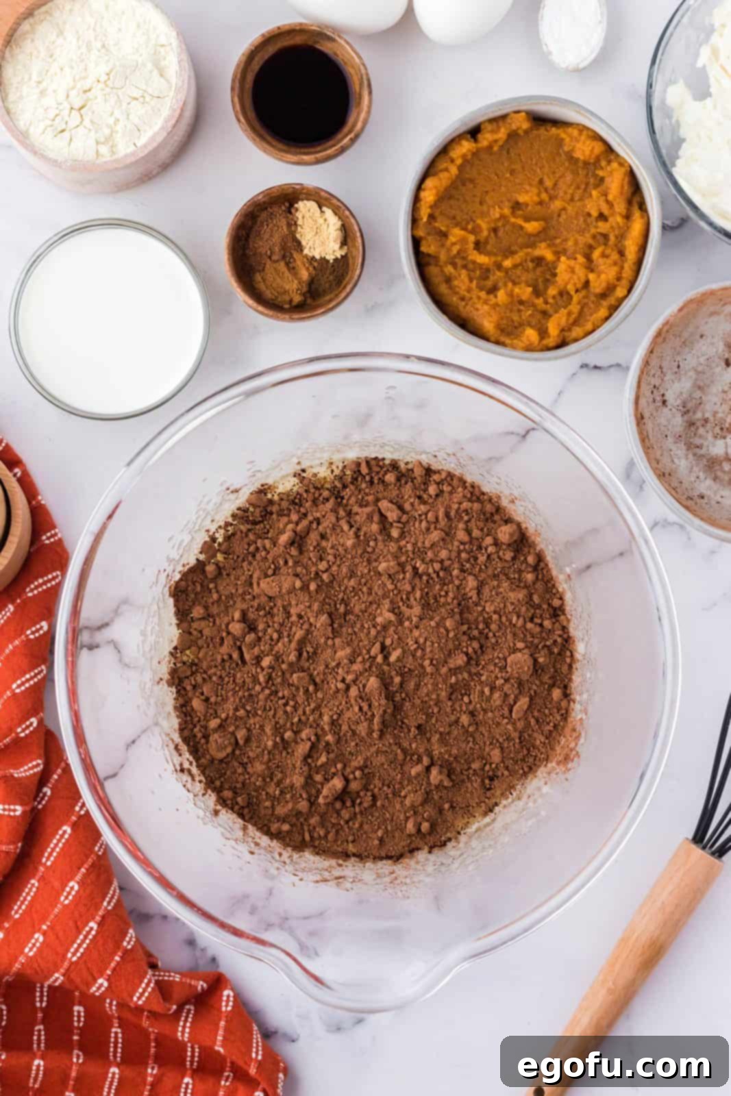 Rich cocoa powder added to the butter and sugar mixture in a bowl, ready to be incorporated for the brownie base.