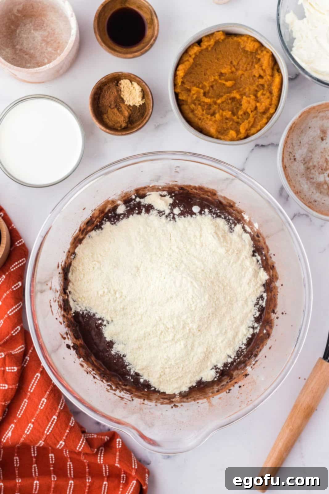 All-purpose flour and baking powder added to the brownie batter, awaiting gentle folding.