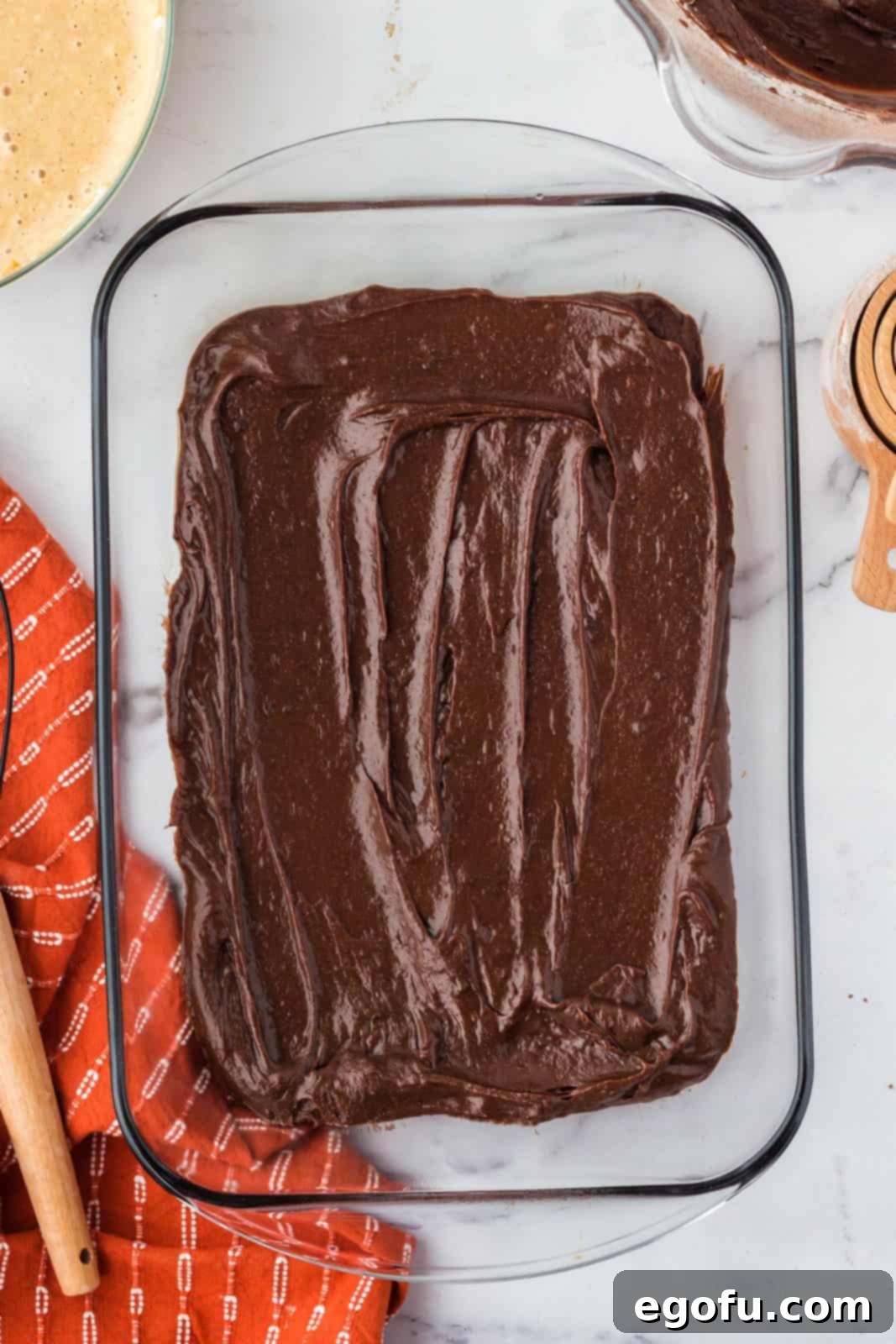Approximately half of the rich brownie mixture evenly spread into the bottom of the baking pan.