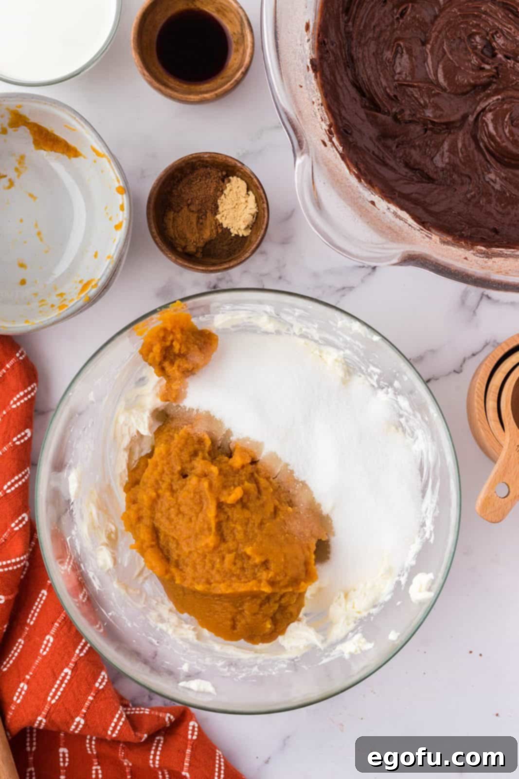 Fluffy beaten cream cheese with pumpkin puree, sugar, and autumn spices added, ready for further mixing.