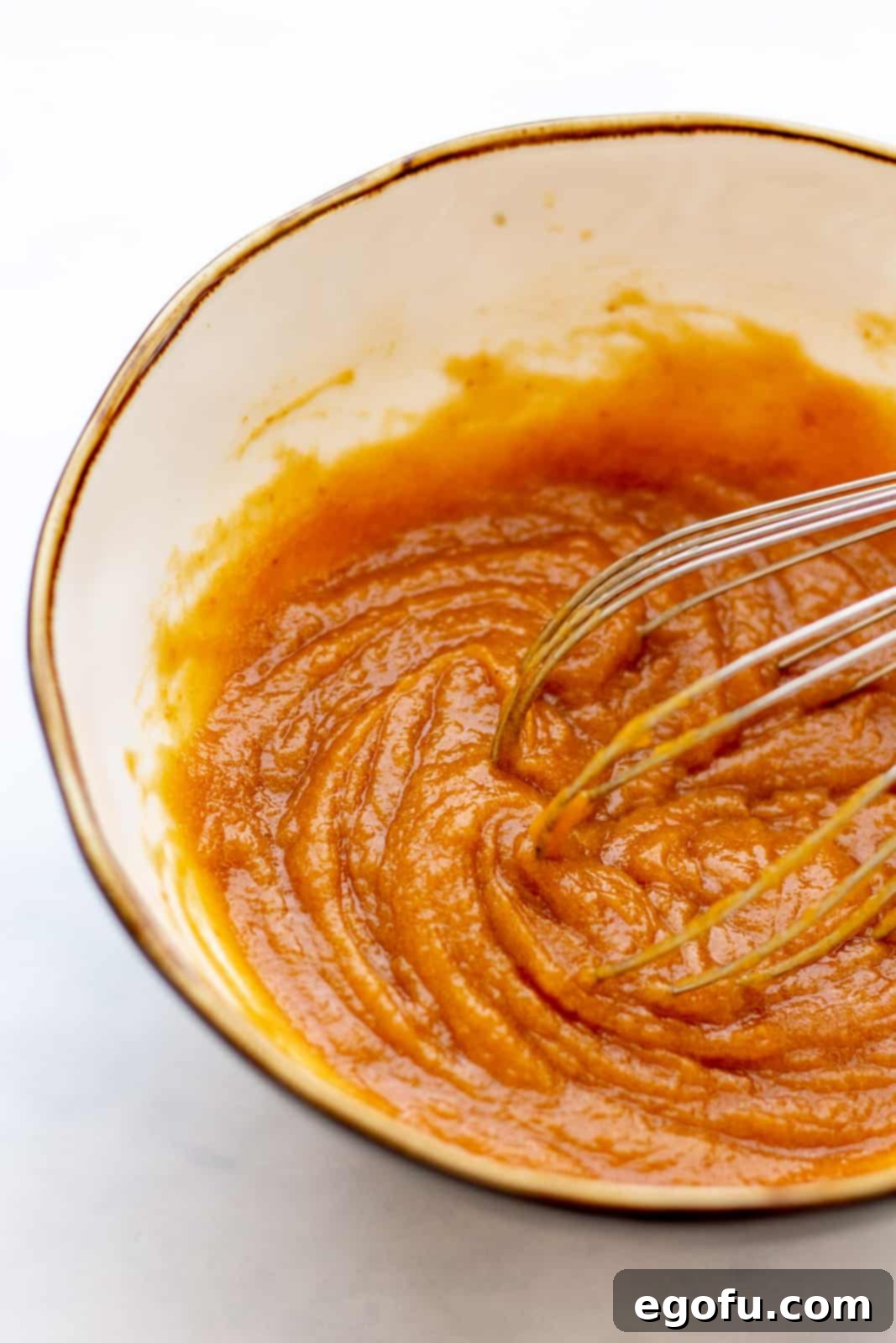 Pumpkin and vanilla being whisked into butter mixture.