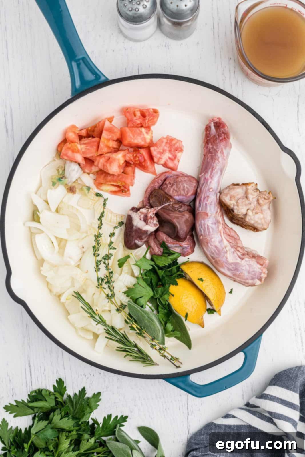 The Definitive Turkey Gravy 5 Turkey neck and gizzards, fresh sage, rosemary, thyme, parsley, chopped onions, lemon wedges, and a chopped beef tomato simmering in a heavy-bottomed pan, releasing their aromatic flavors.