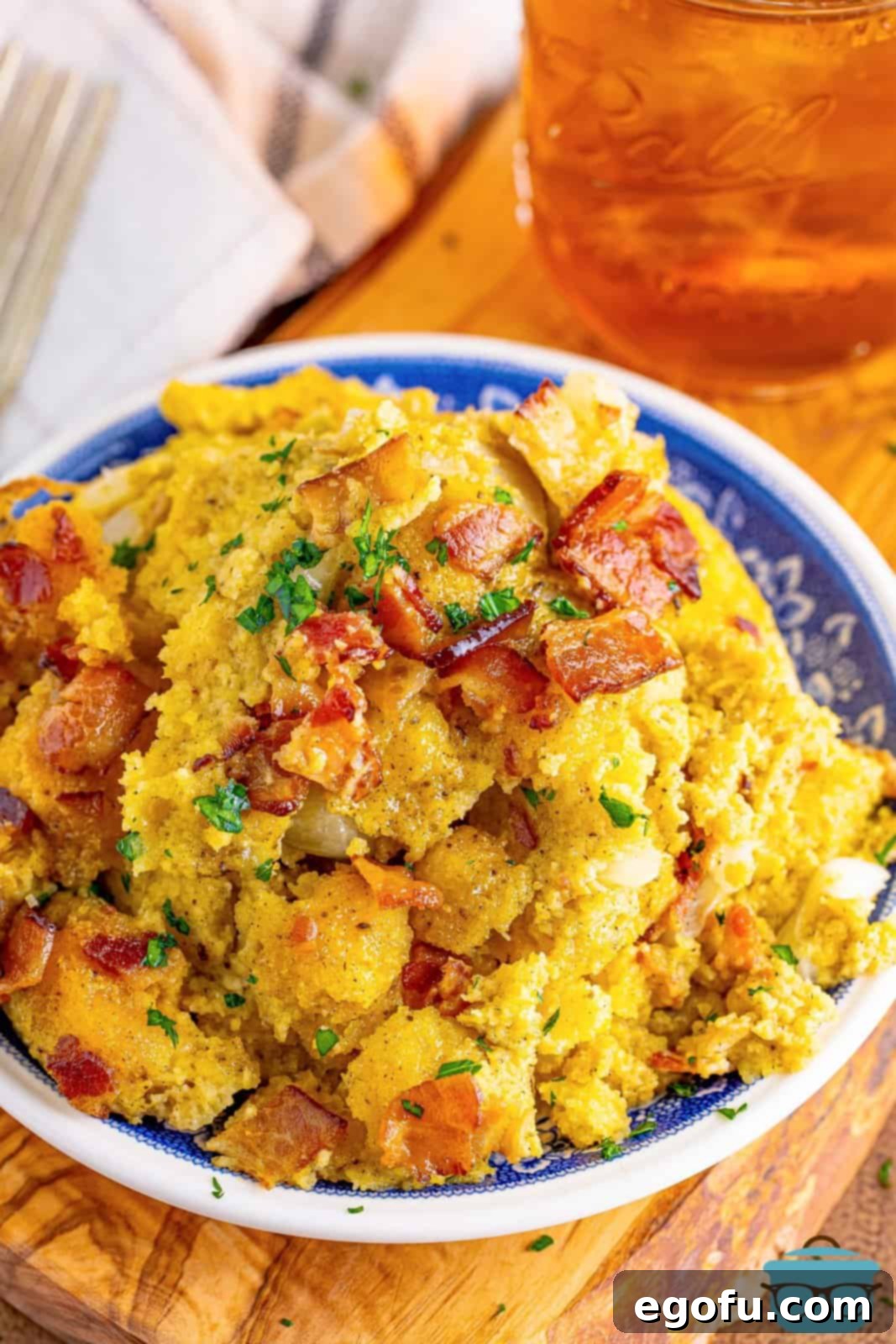 Homestyle Slow Cooker Cornbread Dressing 2 a blue plate topped with slow cooker cornbread dressing with a mason jar of iced tea in the background.