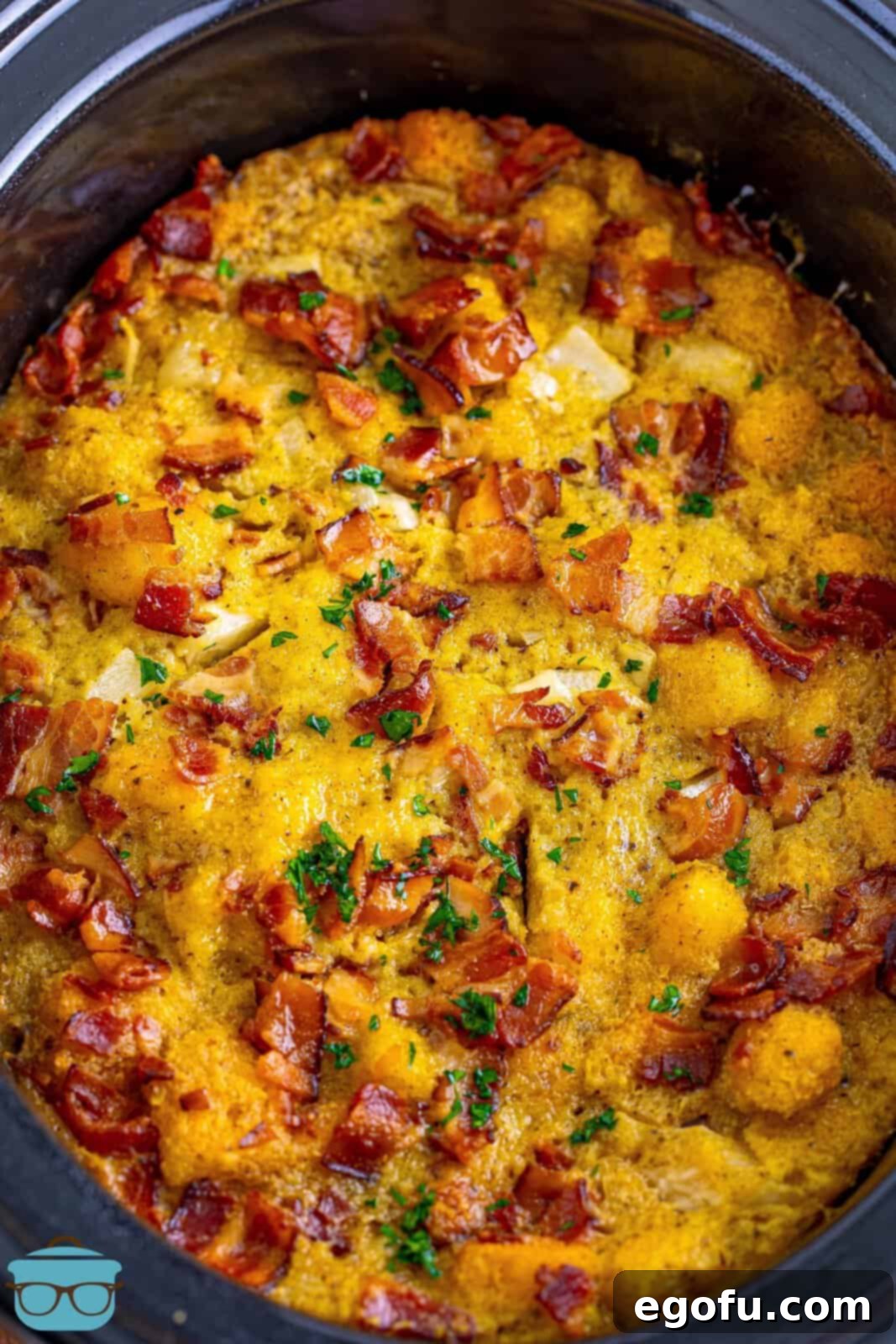 Homestyle Slow Cooker Cornbread Dressing 7 fully cooked cornbread dressing showing in the crock pot with bacon on top.