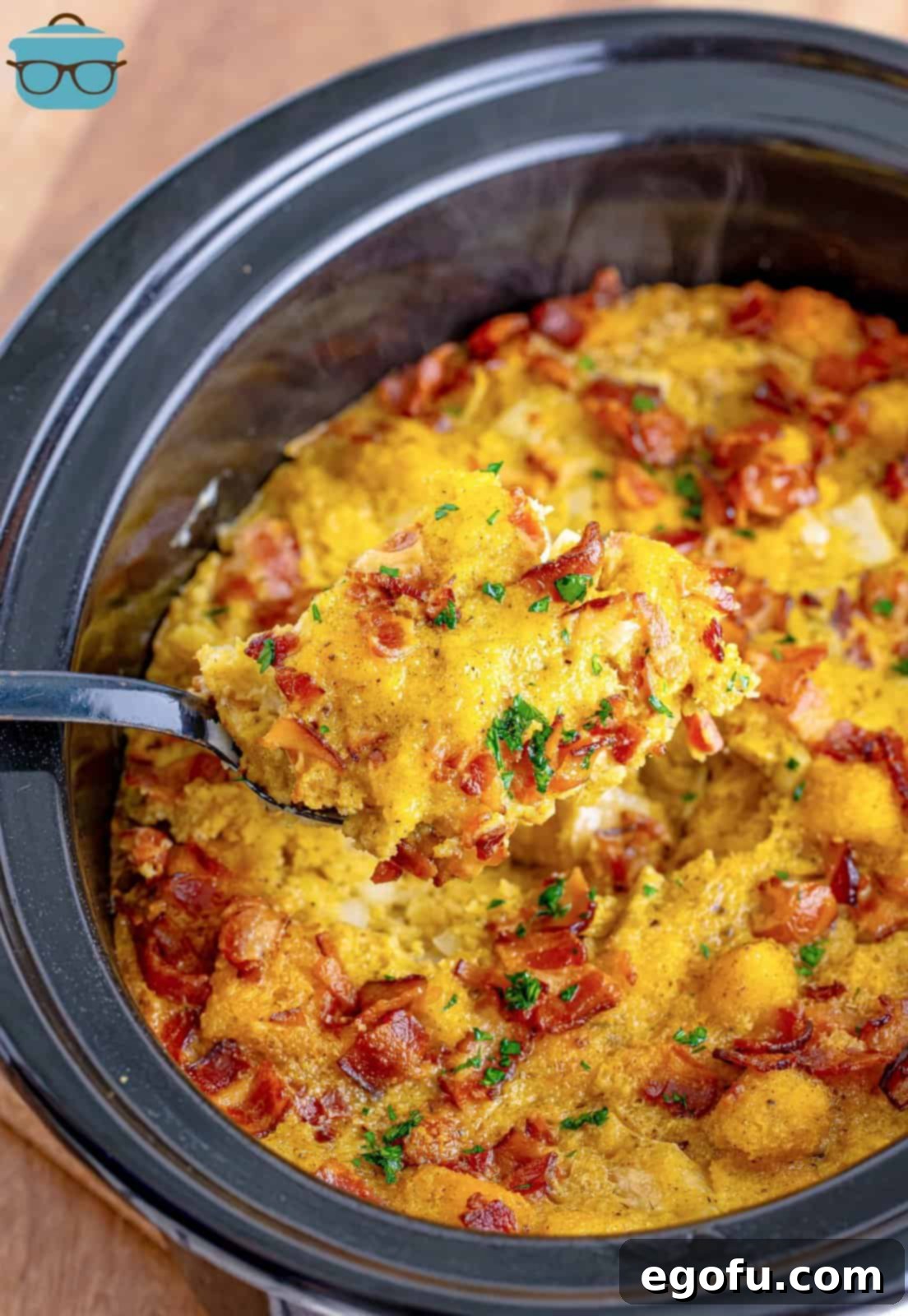 Homestyle Slow Cooker Cornbread Dressing 8 a spoon scooping out some cornbread dressing from an oval slow cooker.