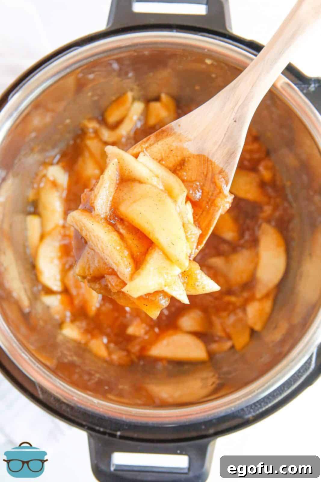 Wooden spoon lifting up Fried Apples out of instant pot.