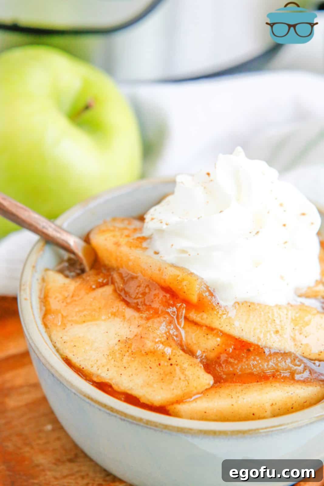 Side view of Instant Pot Fried Apples in bowl with whipped cream and spoon.