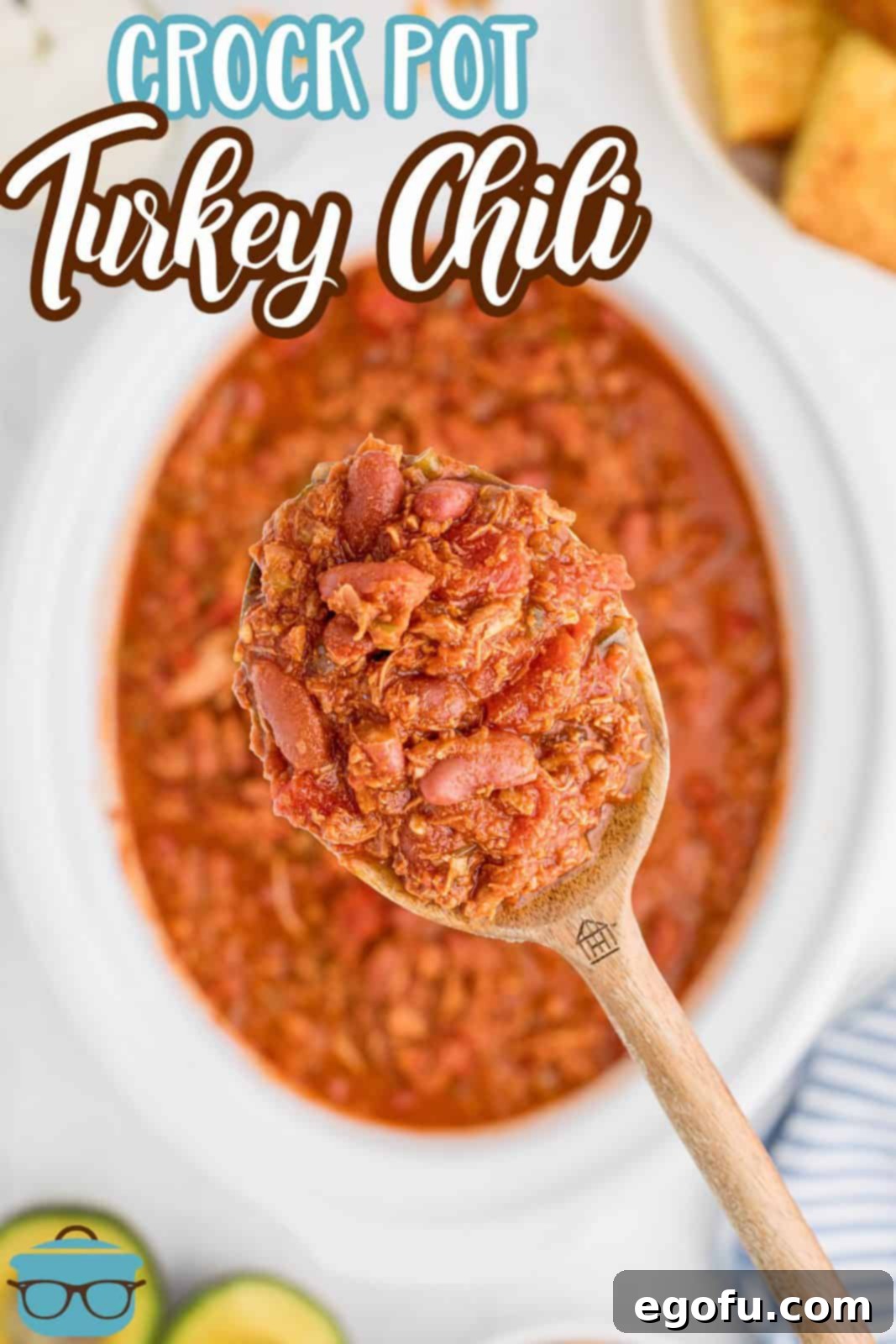 A wooden spoon lifting up Crock Pot Turkey Chili out of crock pot, showing the rich, thick consistency.