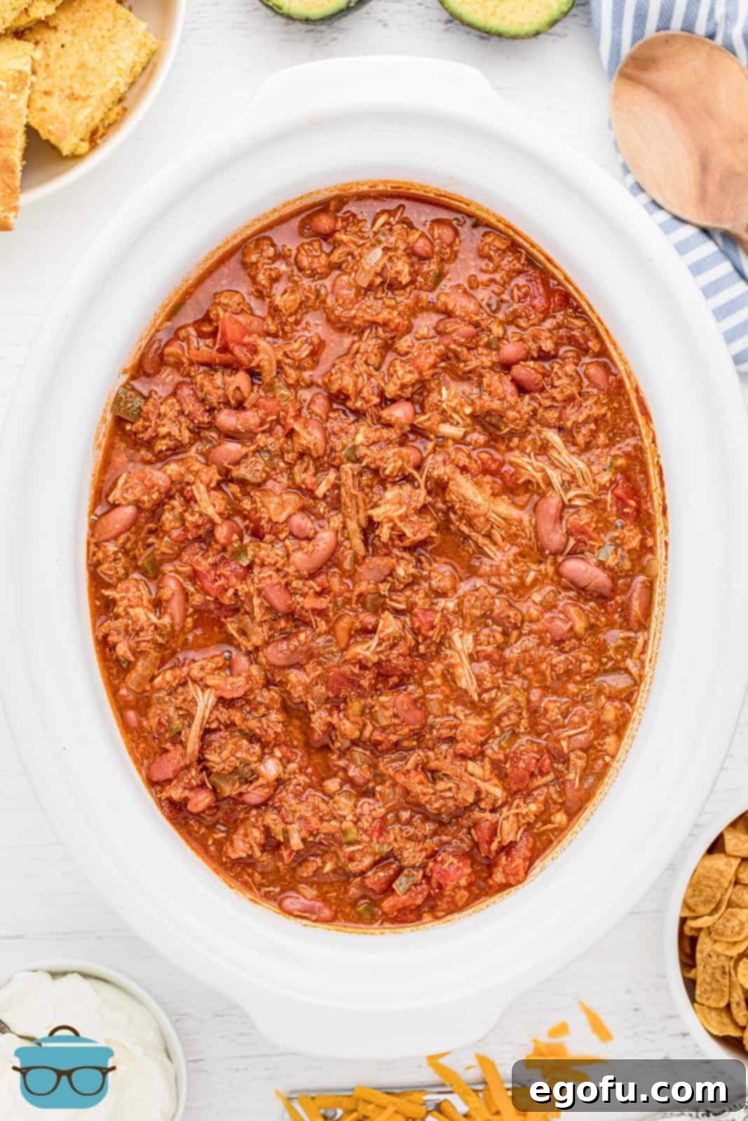 An overhead view of the Crock Pot Turkey Chili simmering in a white crock pot, its rich red color and tender ingredients invitingly ready to serve.