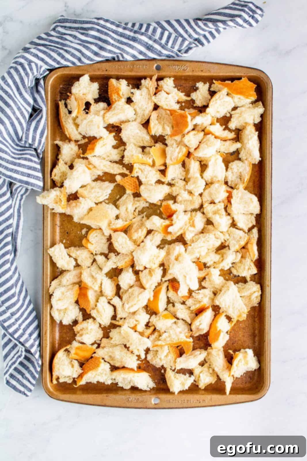 Torn French bread pieces spread on a baking sheet to dry out.
