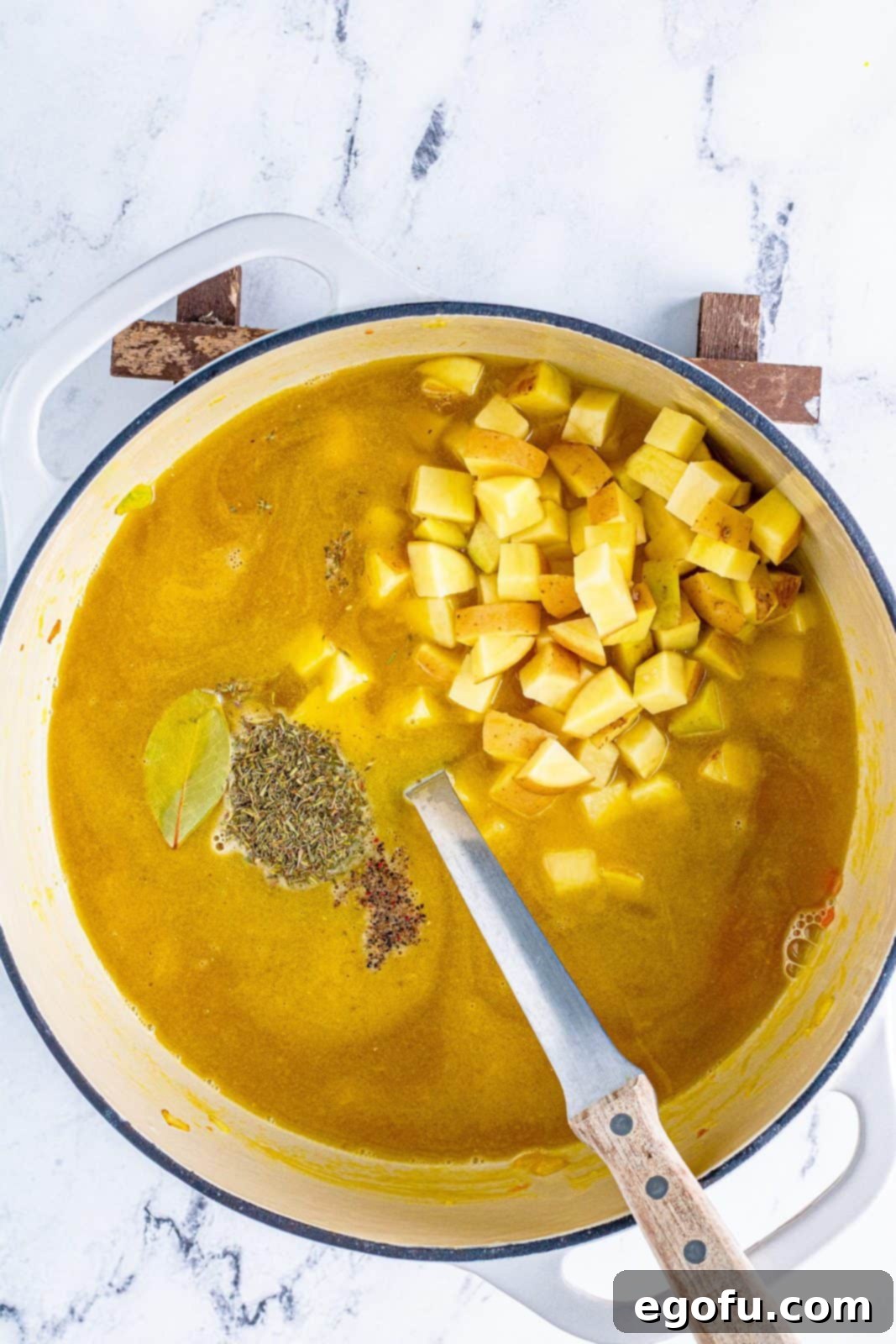 Stock, potatoes, bay leaf, thyme, and pepper added into vegetable mixture.