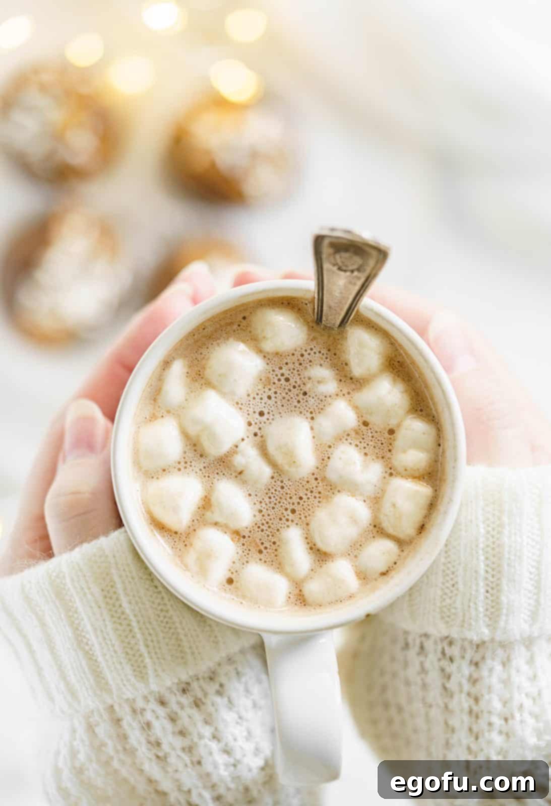 Hand holding melted Chocolate Peanut Butter Hot Cocoa Bomb in white mug.
