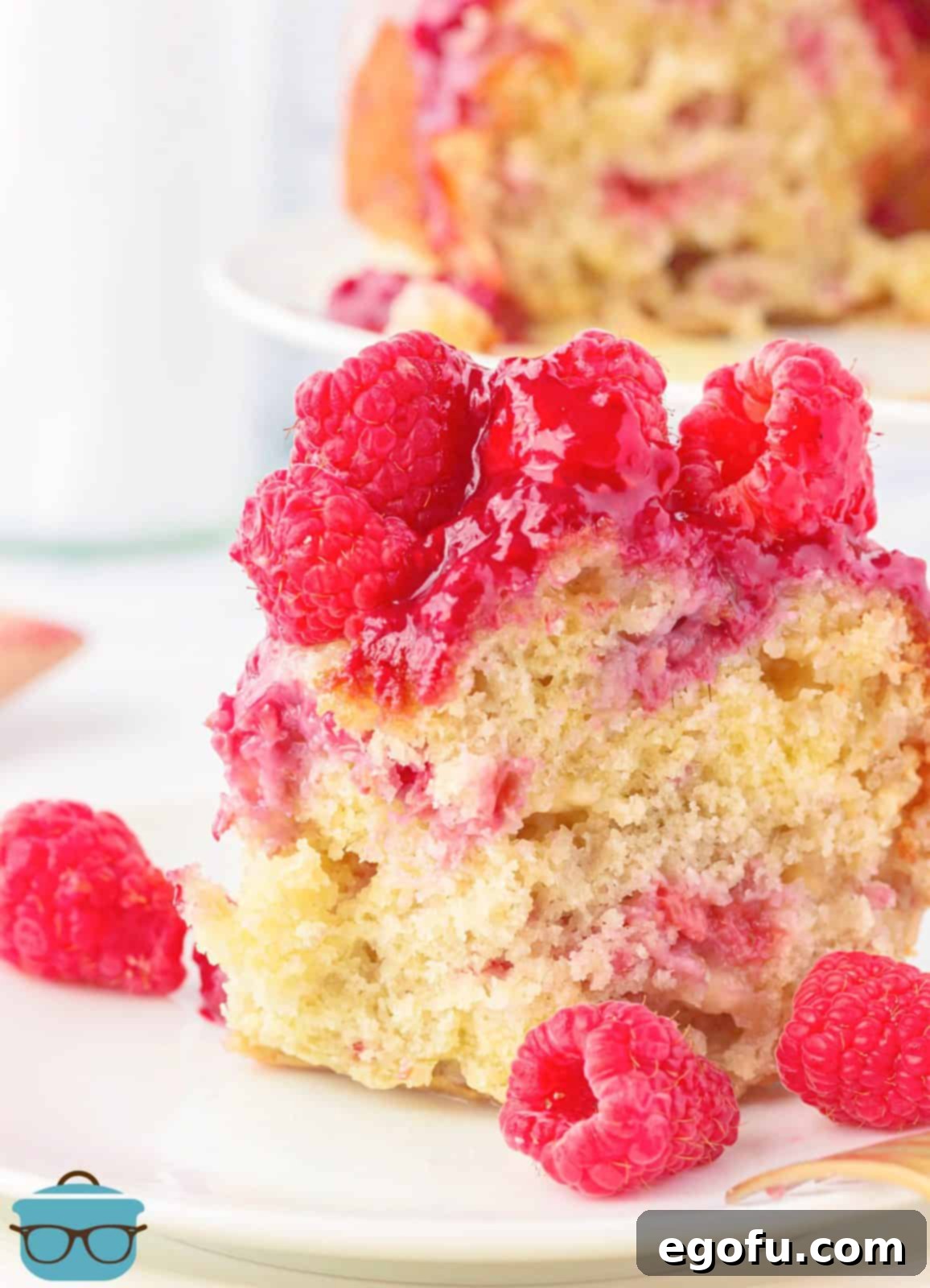Slice of White Chocolate Raspberry Cake on plate with bite taken out.